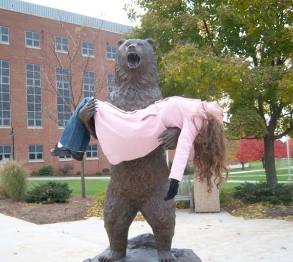 mujer en brazo de estatua de oso