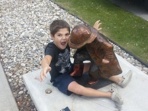 niño jugando con estatua