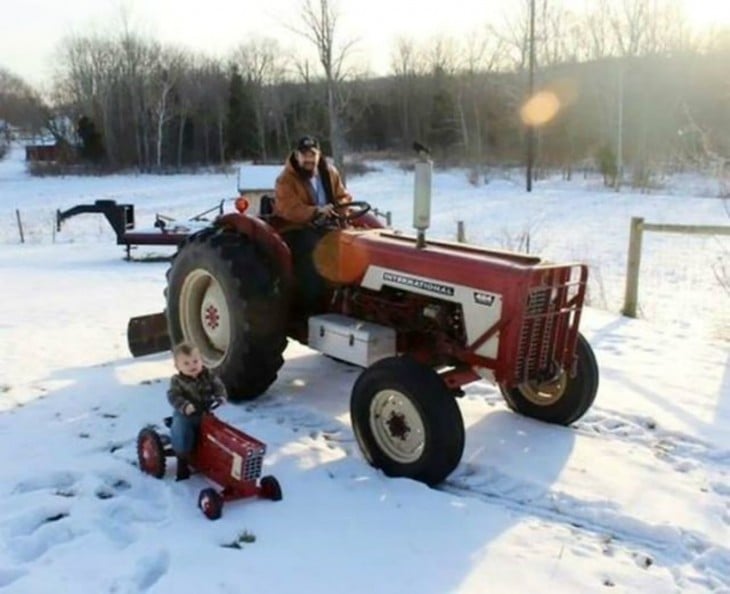 Un padre con su hijo cada uno en un tractor en la nieve 