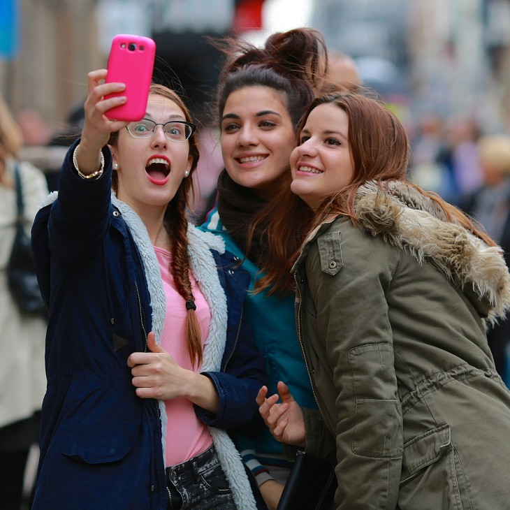 muchachas tomandose selfie con caras en la calle