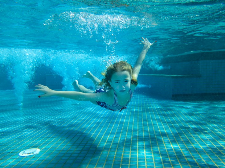 niña nadando bajo la pisicna