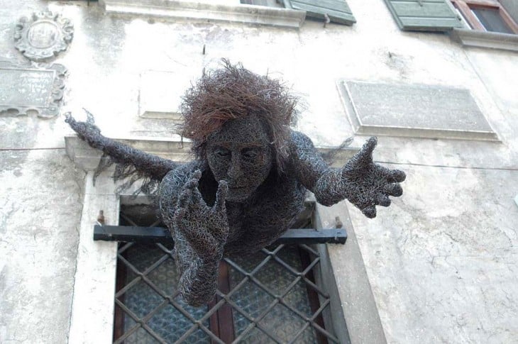 Escultura de alambre con la forma de un chico estirándose por una ventada de Mattia Trotta