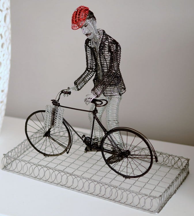 Escultura de alambre con figura de un hombre en su bicicleta 