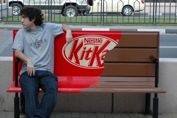 Banca en forma de chocolate KitKat Nestle y un chico sentado en ella 