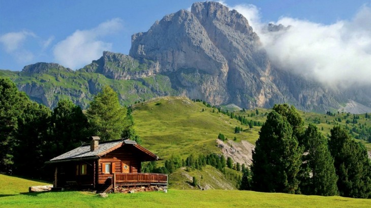 casa de madera con montañas y áreas verdes a su alrededor 