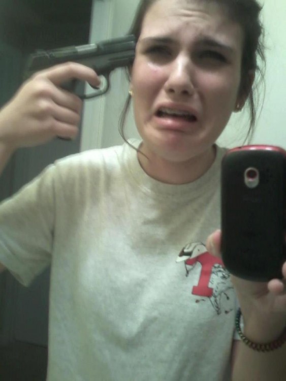 Selfie de una chica con una pistola apuntando a su cabeza