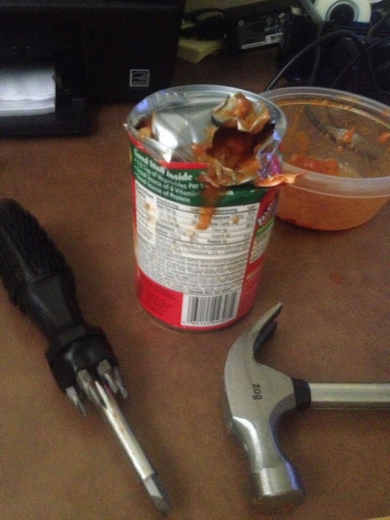 lata de comida abierta con un desarmador y un martillo