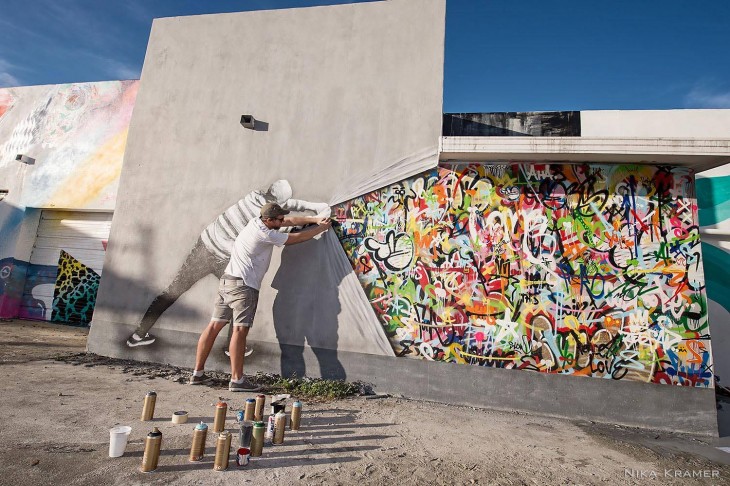 pintura de un dibujo jalando la pintura de una pared y mostrando garabatos de colores en una de las paredes de Miami