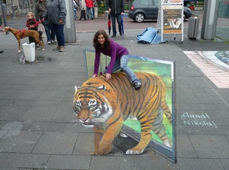 chica montando tigre pintado en la vereda