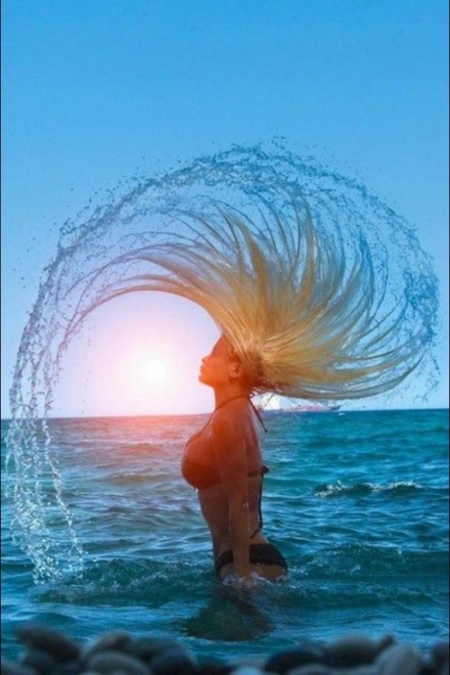 chica moviendo su cabello hacia atrás dentro del mar 