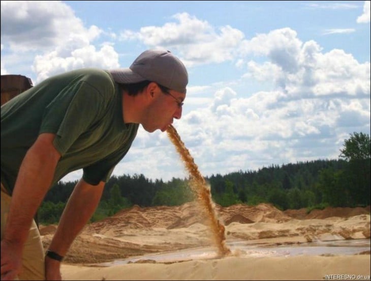 un chico que parece estar vomitando arena en un paisaje 
