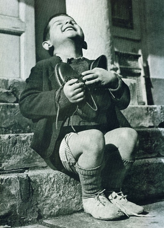 NIÑO AUTRIACO DISFRUTANDO DE UNOS ZAPATOS NUEVOS DESPUES DE LA GUERRA