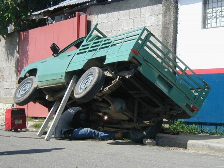 HOMBRE TRATANDO DE ARREGLAR UN CARRO