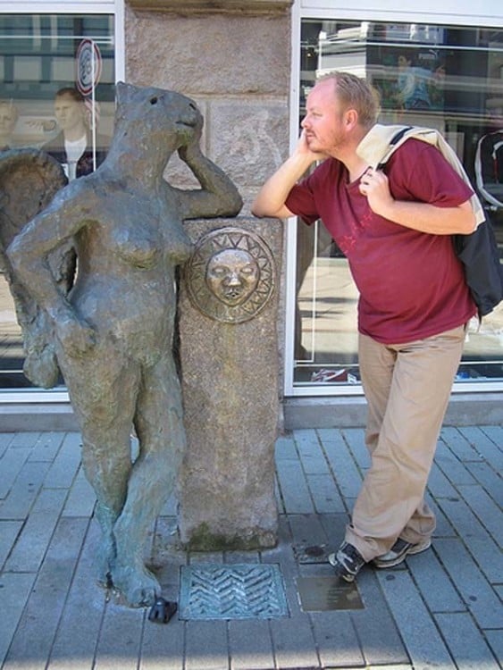 HOMBRE PLATICANDO CON UNA ESTATUA