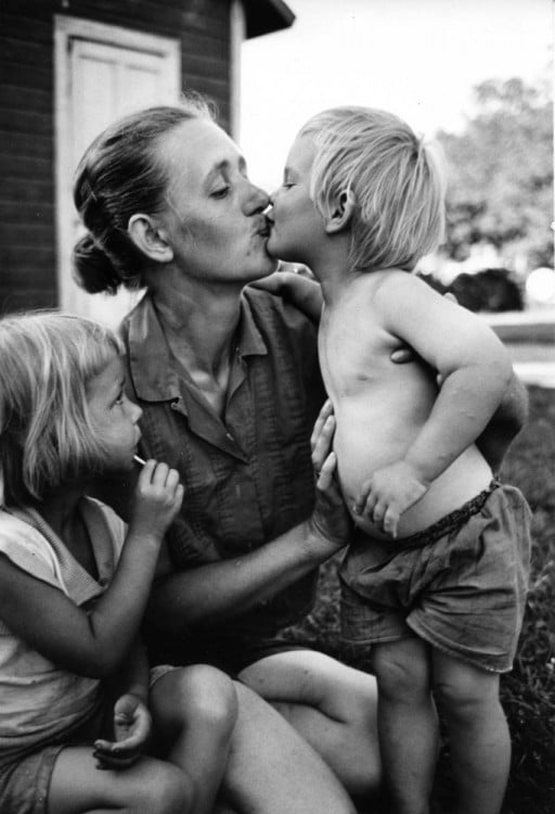 Fotografía de una mujer dando un beso en la boca a su hijo