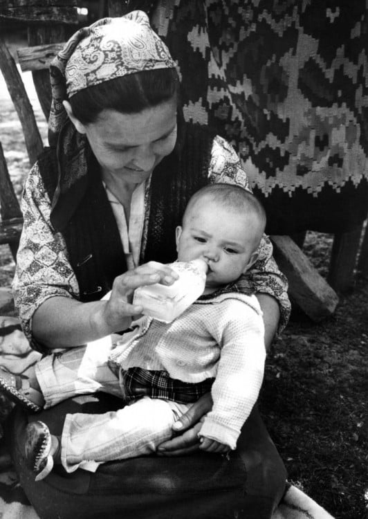 Fotografía de una mujer alimentando a un bebé en sus piernas 