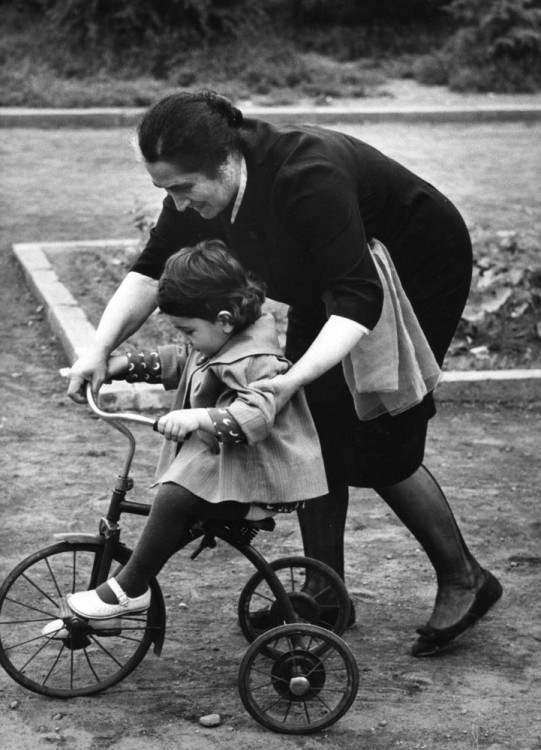 una mujer enseñando a su niño a andar en bici 