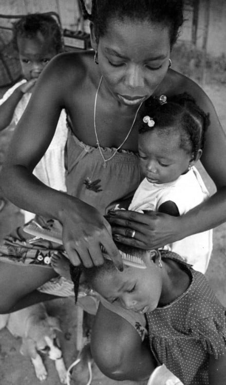 madre con sus hijos alrededor peinando a una de sus hijas 