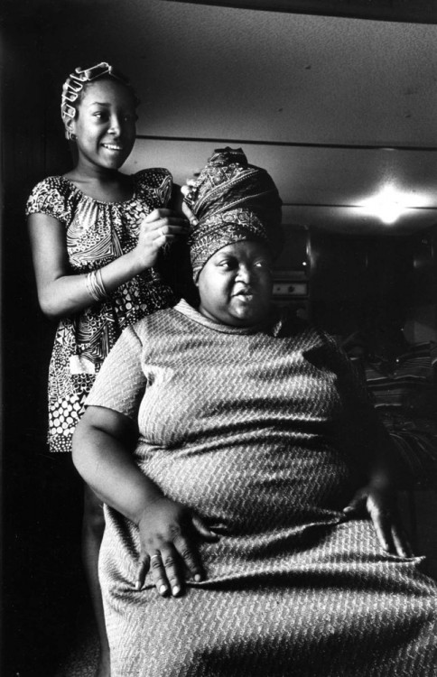 una chica envolviendo el cabello de su madre sentada frente a ella 