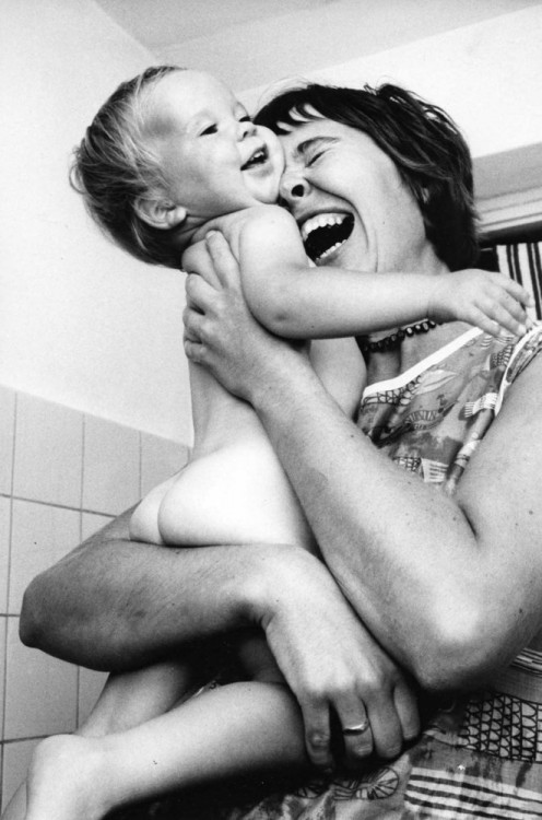 Fotografía de una madre abrazando y riendo con su bebé 