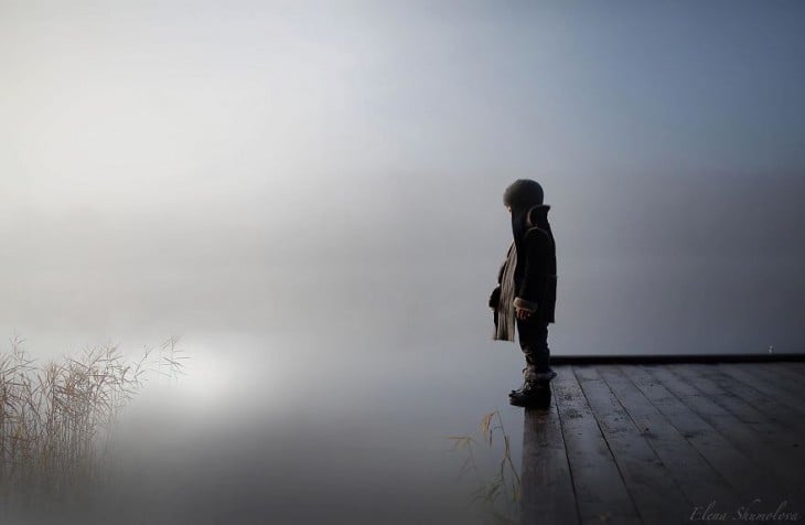 niño parado en el muelle viendo el agua