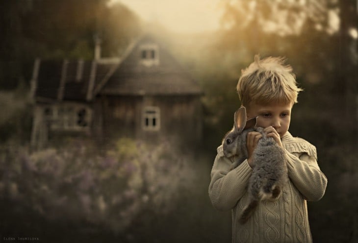 niño con su conejo en frente de la casa