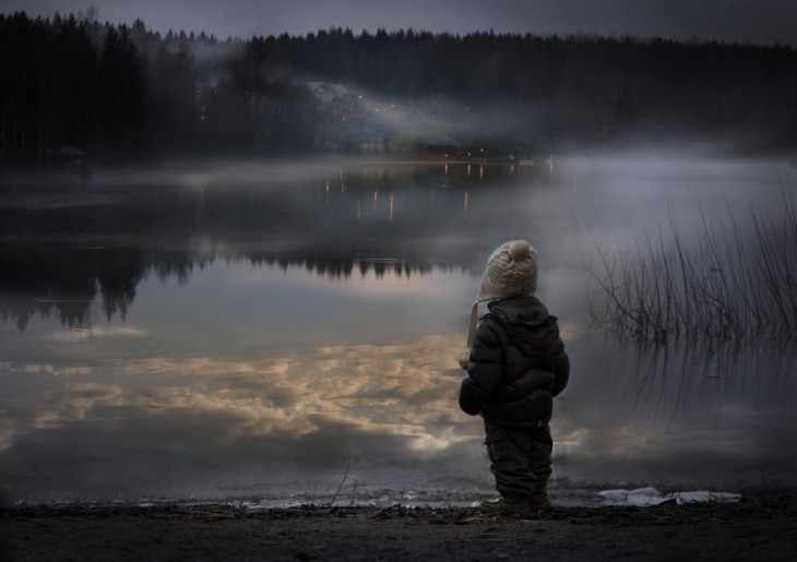 niño viendo el atardecer en un lago