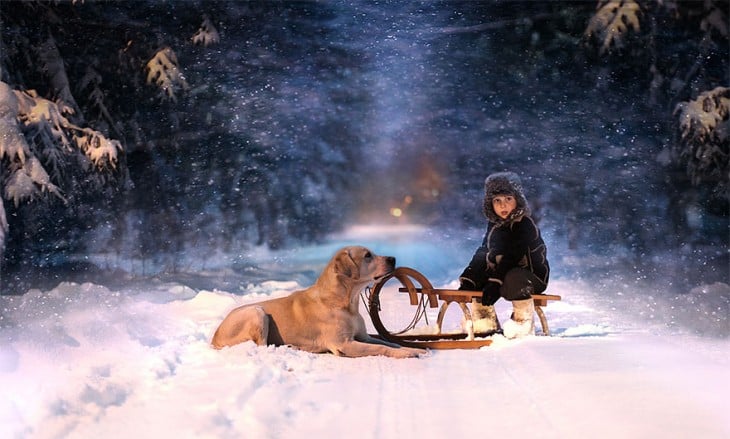 niño con su perro sentado en el trineo