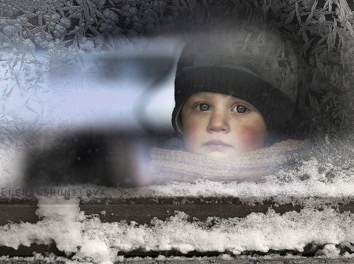 niño en la ventana con nieve