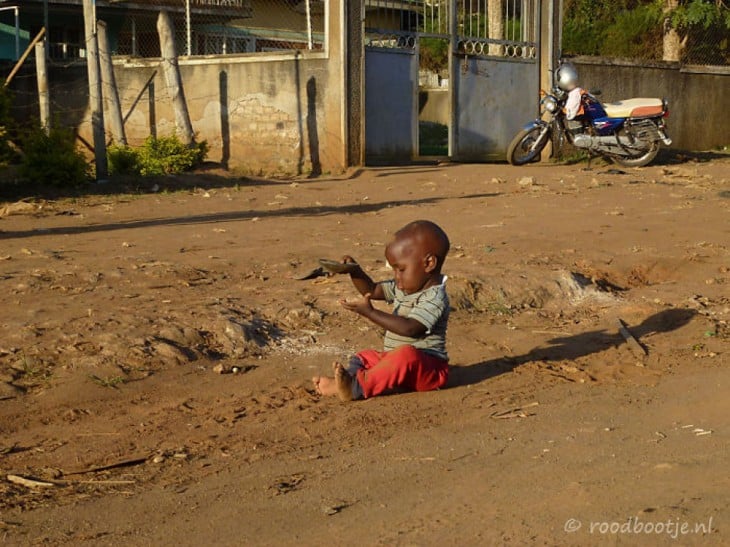 Niño jugando con arena en Uganda