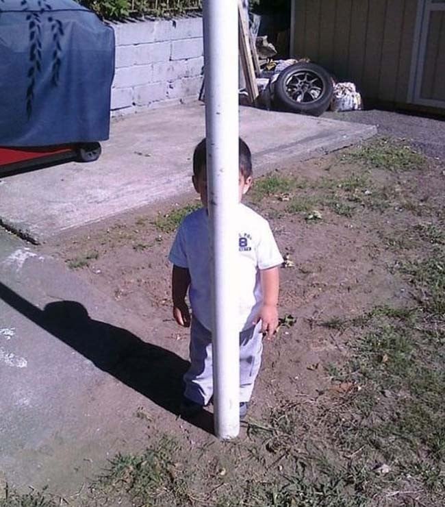 niño escondiéndose detrás de un poste