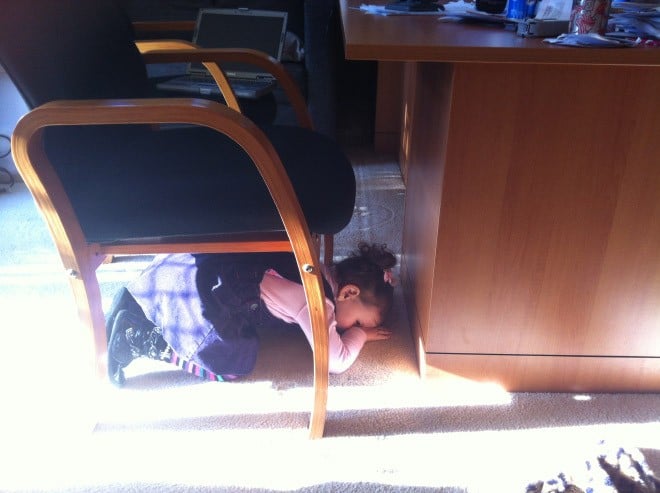 niño escondiéndose debajo del escritorio