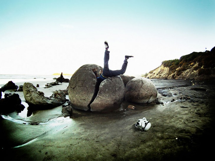 hombre metido en media roca circular de una playa muy fria