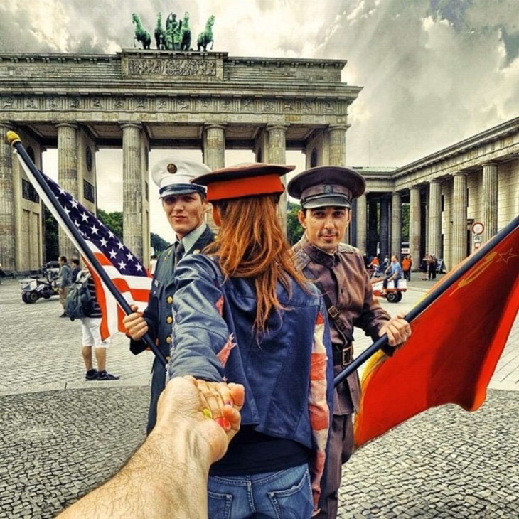 Dos actores con uniformes de soldados posan con Natalia en la Puerta de Brandemburgo de Berlín. 