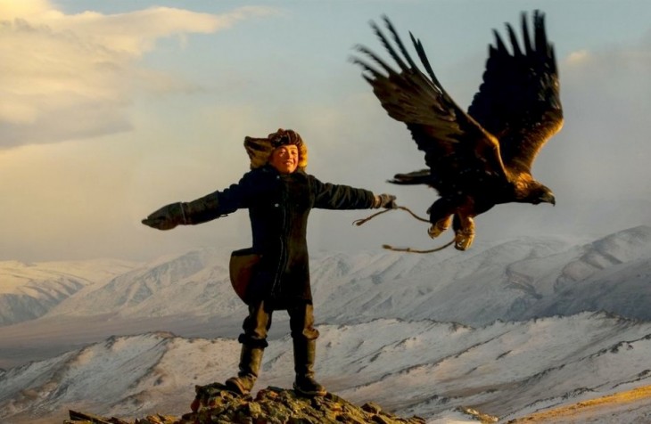 Niño arriba de una montaña junto a un águila volando en Mongolia 