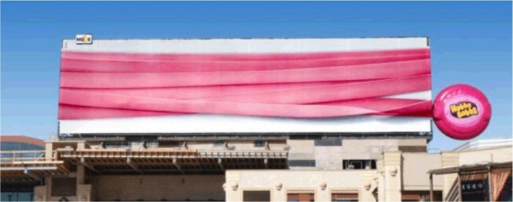 goma rosada envuelve edificio en publicidad de goma de mascar