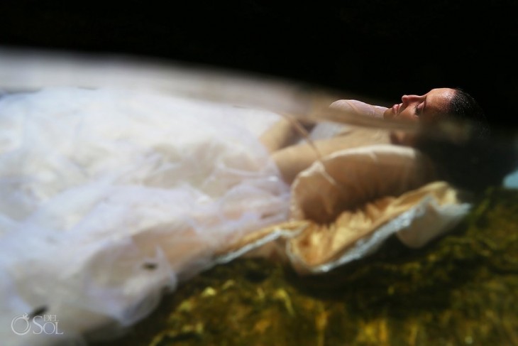 mujer vestida de novia acostada en el agua mirando hacia arriba 