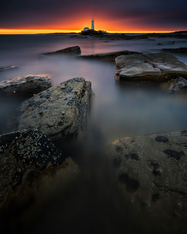 atardecer con un faro en el horizonte