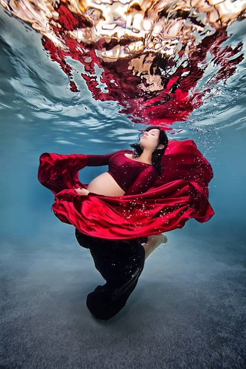 mujer embarazada bajo el agua vestida de rojo