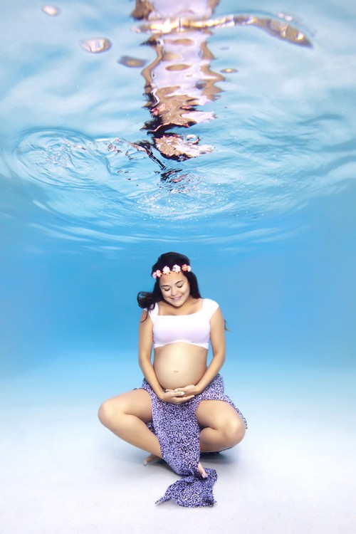 mujer embarazada bajo el agua agarrándose la panza