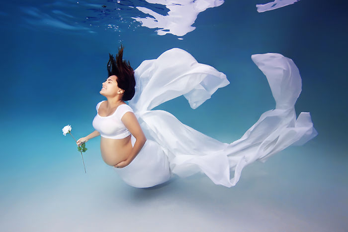 mujer embarazada bajo el agua vestida de blanco