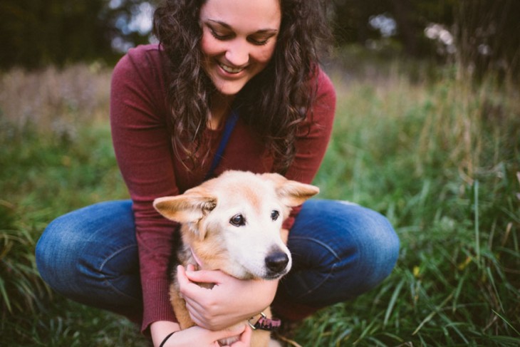 muchacha sentada en el pasto abrazando a su perro