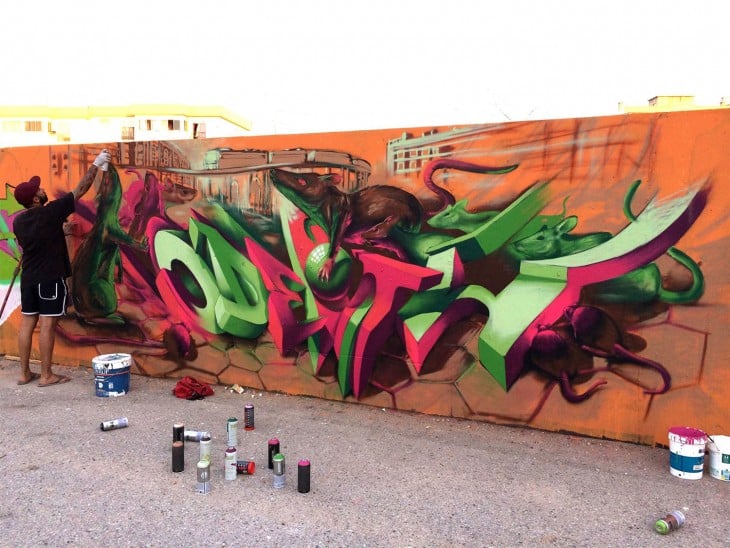 Un hombre pintando un grafiti sobre una pared 