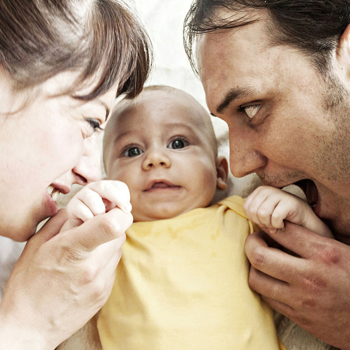 padre y madre apretando a su bebe