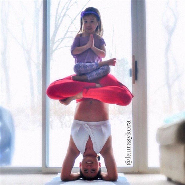 posicion de yoga con la cabeza y la niña arriba de ella