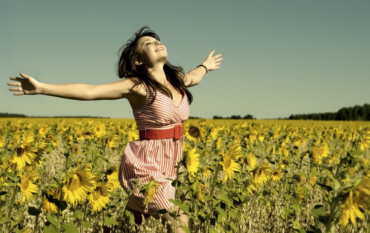 mujer feliz corriendo en un jardin lleno de girasoles