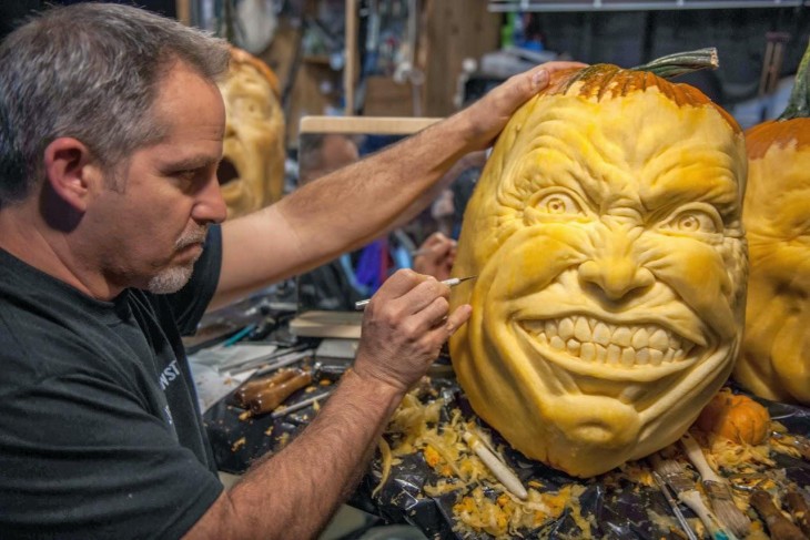 hombre que esta esculpiendo una calabaza de halloween