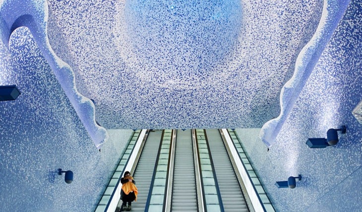 impresionante estacion del metro que tiene un circulo en el techo y largas escaleras