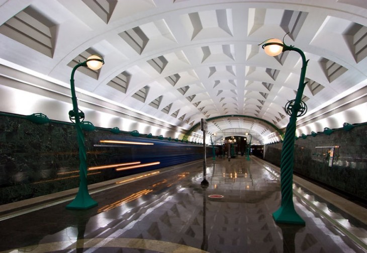 pasillo de una estacion de metro con largos faroles de color verde