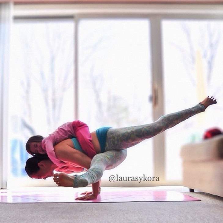 madre cargando a su pequeña hija en posicion de yoga